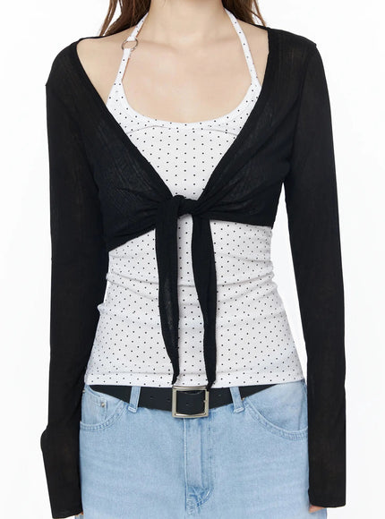 Sheer Tie-Front Wrap Crop Cardigan IL502 Black close-up front torso detail shot showing tie-front knot sheer fabric texture open neckline and polka dot inner tank