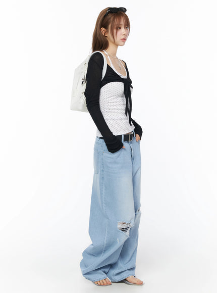 Sheer Tie-Front Wrap Crop Cardigan IL502 Black side model shot with white backpack and sunglasses on head sheer crop cardigan layered over polka dot top with distressed jeans
