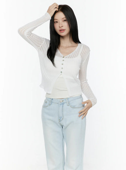 Sheer V-Neck Cardigan IL506 White front shot model hand in hair one hand on hip wearing open sheer ribbed knit cardigan with flared light blue jeans
