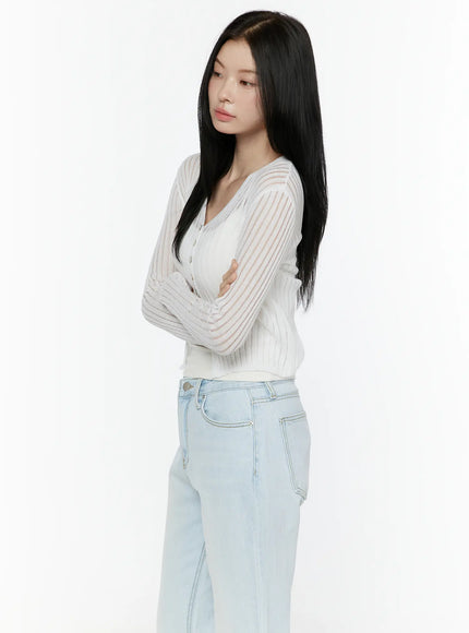 Sheer V-Neck Cardigan IL506 White side shot model standing arms crossed upper-body view highlighting sheer stripe ribbed knit sleeves and V-neckline with button placket