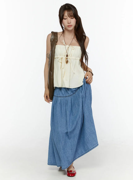 Shirred Cami Top CL508 Light beige full-length front shot on model with spaghetti straps, double drawstring ties, flowy silhouette, styled with blue denim maxi skirt and red flats