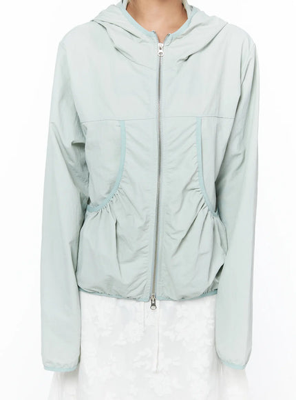 Shirred Hooded Windbreaker CU523 Mint detail front close-up model showing silver zipper shirred curved pockets and mint contrast piping on lightweight nylon fabric