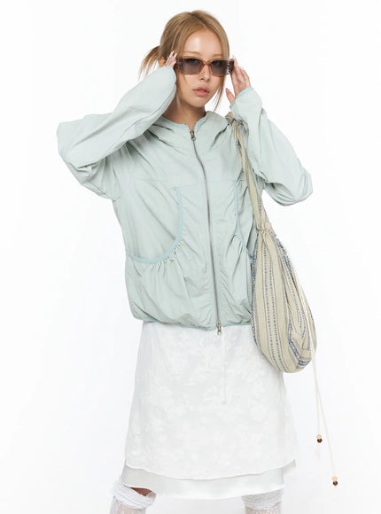 Shirred Hooded Windbreaker CU523 Mint front model wearing sunglasses and patterned shoulder bag adjusting sunglasses ruched pocket and zip detail visible