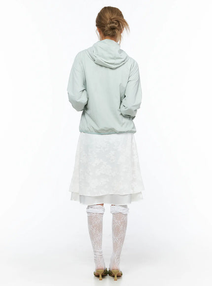 Shirred Hooded Windbreaker CU523 Mint back model full-length view hooded windbreaker showing hood shape and elastic hem over white layered midi skirt and lace socks