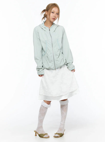 Shirred Hooded Windbreaker CU523 Mint front model standing hands at sides hooded zip-up with shirred hem detail over white layered midi skirt and lace knee socks