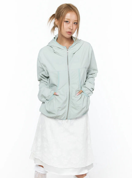 Shirred Hooded Windbreaker CU523 Mint front model hands in pockets zip-up hooded jacket with shirred curved pockets over white layered skirt and lace knee socks
