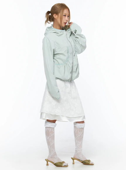 Shirred Hooded Windbreaker CU523 Mint side model touching hood lightweight nylon windbreaker with ruched waist pockets over white layered skirt and lace socks