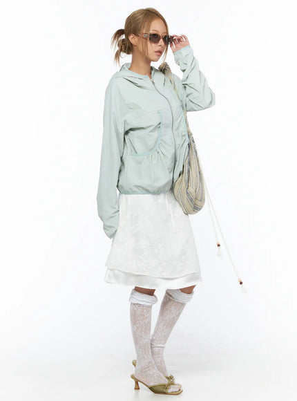 Shirred Hooded Windbreaker CU523 Mint side model wearing sunglasses and patterned crossbody bag full-length styling with white layered midi skirt and lace knee socks