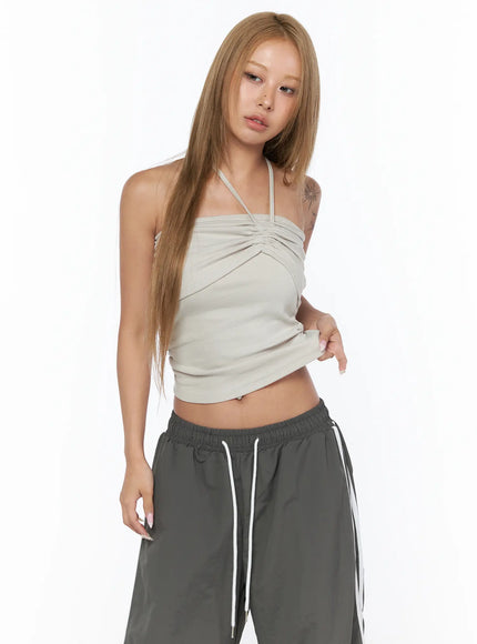 Shirred Strap Tube Top CU523 Light beige S/M front model shot angled pose model touching hem gathered halter neckline ruched sides gray track pants