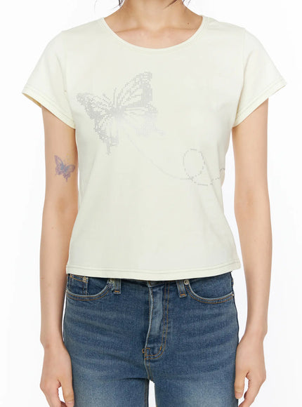Short Sleeve Graphic Tee CU530 Light yellow detail close-up shot on model torso revealing full butterfly rhinestone and dotted trail graphic print