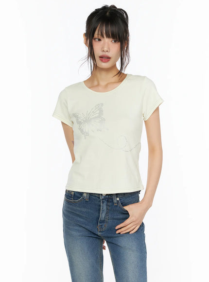 Short Sleeve Graphic Tee CU530 Light yellow front close-up shot model facing camera showing silver butterfly rhinestone graphic on cropped tee