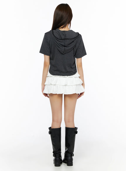Short Sleeve Hooded Jacket IL523 Black back view on model showing striped hood and crop length, paired with white tiered pleated mini skirt and black knee-high buckle boots