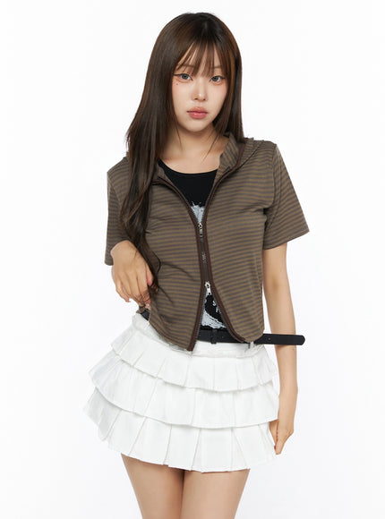 Short Sleeve Hooded Jacket IL523 Brown front view on model with hood down, brown stripe zip-up cropped jacket, styled with white tiered pleated mini skirt and black belt