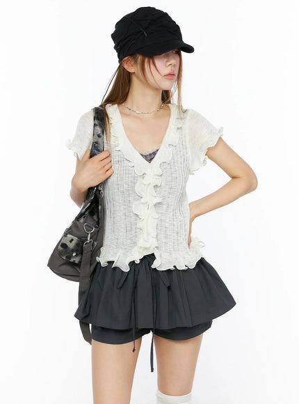 LEWKIN Short Sleeve Ruffle Cardigan CL501 White S/M front model shot styled with black cap and bag, sheer ribbed knit with cascading ruffles