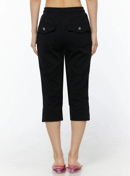 Side Slit Cropped Track Pants IL509 Black back view on model showing two flap pockets with silver snap buttons elasticated waistband and side slit hem details