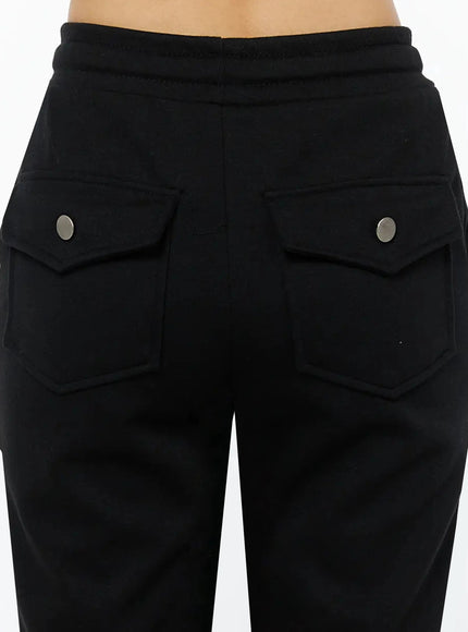 Side Slit Cropped Track Pants IL509 Black close-up back detail showing dual flap cargo pockets with silver snap buttons and elasticated ribbed waistband