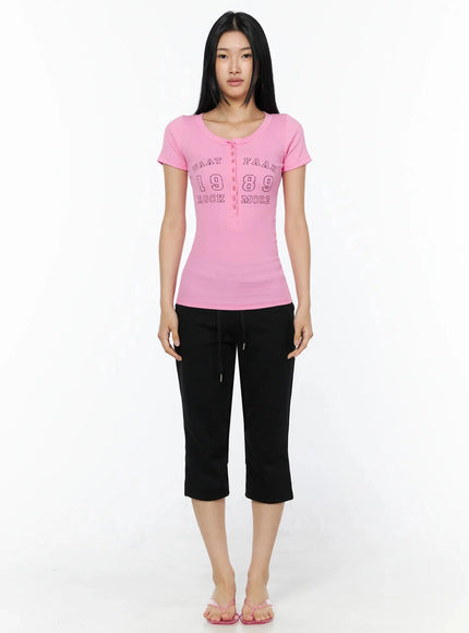 Side Slit Cropped Track Pants IL509 Black full-body front view on model in pink 1989 graphic henley tee barefoot with pink flip flops straight standing pose