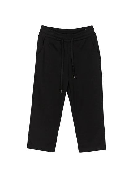 Side Slit Cropped Track Pants IL509 Black flat-lay front view showing full garment with drawstring waistband side pockets and cropped straight leg silhouette