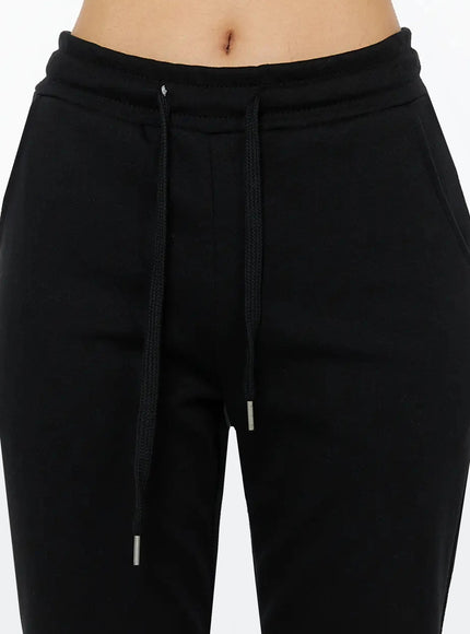 Side Slit Cropped Track Pants IL509 Black close-up detail of front waistband showing drawstring with silver aglets and elasticated waistband fleece texture