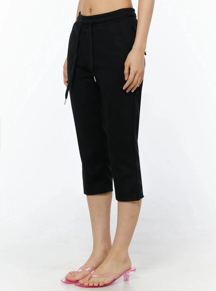 Side Slit Cropped Track Pants IL509 Black side view on model showing drawstring waist, side cargo snap pocket detail, and hem slit with pink heeled sandals