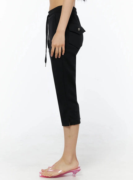 Side Slit Cropped Track Pants IL509 Black side view on model cropped at waist showing side cargo pocket with silver snap button and tapered cropped leg silhouette