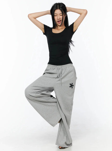 Silky Shirred Short Sleeve Tee IL509 Black dynamic front shot model arms raised hands behind head showing wide-leg silhouette of pants movement pose
