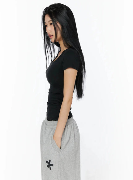 Silky Shirred Short Sleeve Tee IL509 Black side shot model profile view showcasing ruched side seam waist shirring detail fitted crop length with gray wide-leg sweatpants