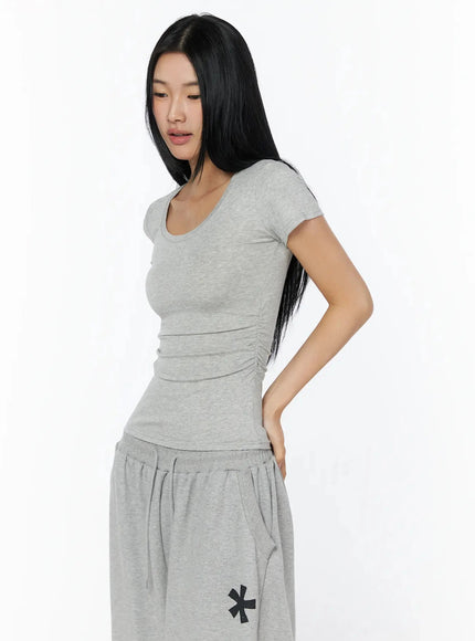 Silky Shirred Short Sleeve Tee IL509 Gray side shot model looking down showing ruched side seam detail scoop neck fitted silhouette with gray sweatpants