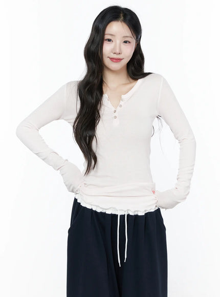 Slim-Fit Henly Neck Long Sleeve Tee IU525 Light pink front model portrait smiling, hands on hips showing ruffle hem and thumbhole sleeves