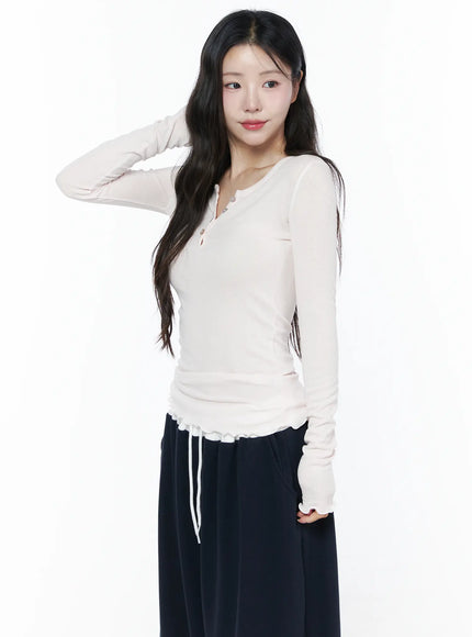 Slim-Fit Henly Neck Long Sleeve Tee IU525 Light pink side model shot hand raised, slim ribbed body with ruffle hem and thumbhole cuffs