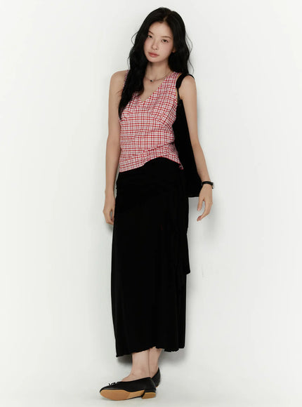 Slim Fit Plaid Sleeveless Top CL520 Red front shot on model against grey wall styled with black maxi skirt and black cardigan holding bag