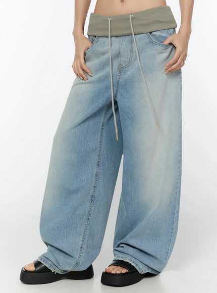 Solene Vintage Washed Foldover Baggy Jeans IU524 Blue front close-up on model showing hands resting on waistband ultra wide-leg washed denim and drawstring detail