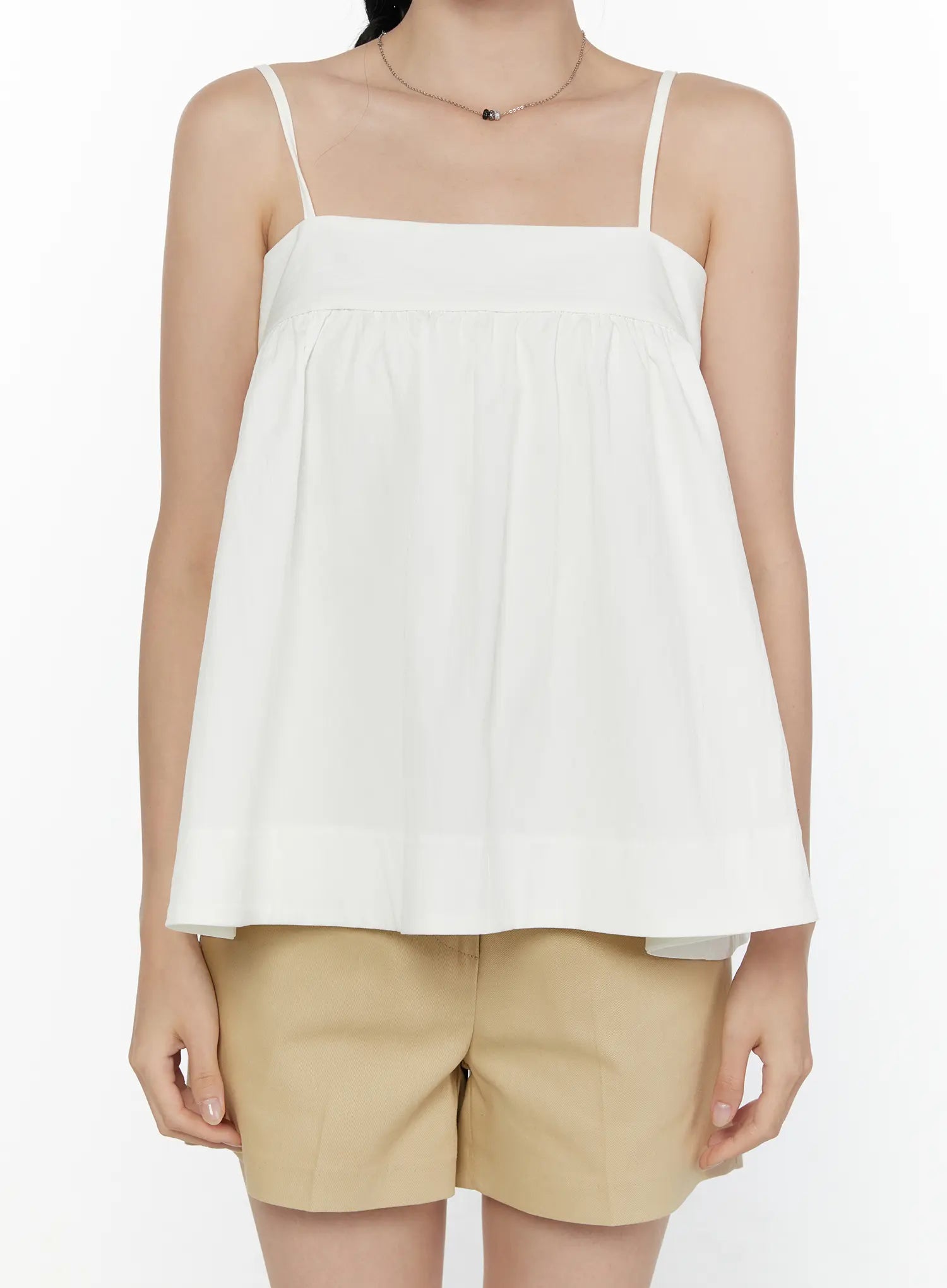 Square Neck Babydoll Cami Top CL520 White cropped front shot on model displaying square neckline, empire gather detail, and flowy hem over beige shorts