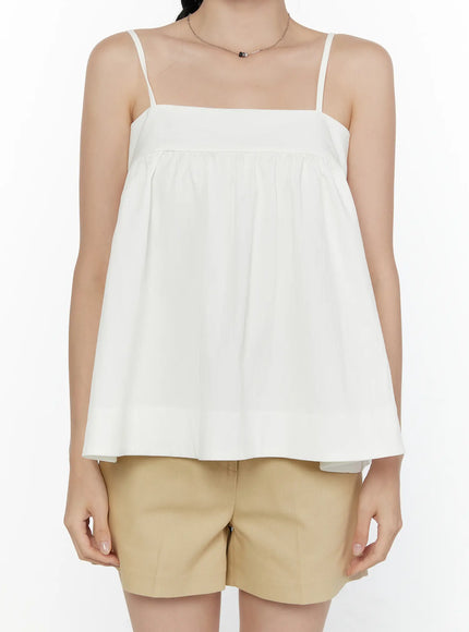 Square Neck Babydoll Cami Top CL520 White cropped front shot on model displaying square neckline, empire gather detail, and flowy hem over beige shorts