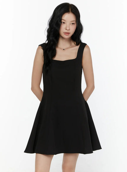 Square Neck Mini Dress CL521 Black front shot on model with hands behind back emphasizing square neckline and fitted flared silhouette