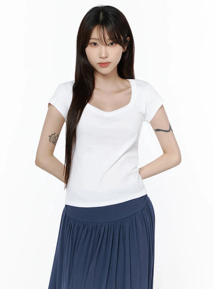 Square Neck Short Sleeve Tee IL502 White front shot on model with hands behind back, highlighting square neckline and fitted short sleeve silhouette with navy skirt