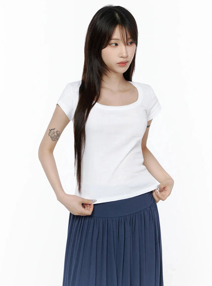 Square Neck Short Sleeve Tee IL502 White three-quarter front shot on model adjusting hem, square neck detail visible, styled with navy gathered skirt, casual pose