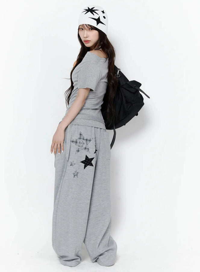 LEWKIN Star Graphic Wide Leg Sweatpants IL506 Gray side shot on model with beanie and backpack showing star appliqué detail on wide leg