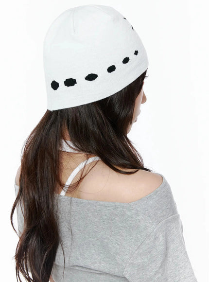 Star Knit Beanie IL506 White back on-model shot, female model facing away showing black dot intarsia pattern along beanie band, paired with grey off-shoulder top