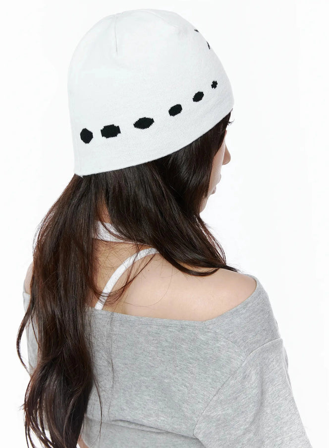 Star Knit Beanie IL506 White back on-model shot, female model facing away showing black dot intarsia pattern along beanie band, paired with grey off-shoulder top