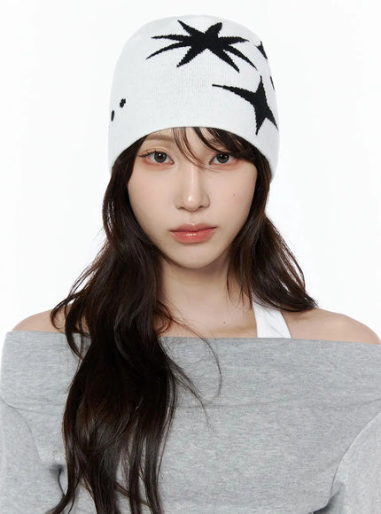 Star Knit Beanie IL506 White close-up front on-model, female model direct front gaze, black starburst and four-point star intarsia knit pattern clearly visible