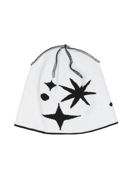 Star Knit Beanie IL506 White flat product shot inside-out view, white knit beanie showing reverse black starburst intarsia pattern with black overlock seam detail at crown