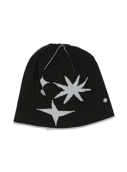 Star Knit Beanie IL506 Black flat product shot, black knit beanie laid flat showing grey starburst and four-point star intarsia pattern with exposed overlock seam at crown