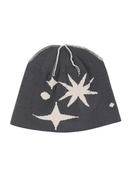 Star Knit Beanie IL506 Grey flat product shot, dark grey knit beanie laid flat showing cream white starburst intarsia pattern with exposed overlock seam detail at crown