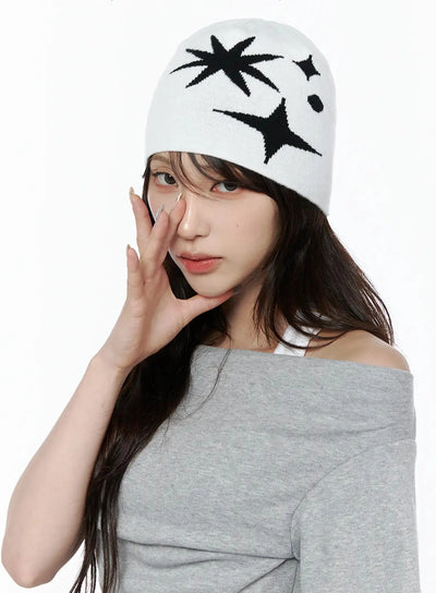 LEWKIN Star Knit Beanie IL506 White front on-model close-up, female model hand raised to face, black star burst intarsia knit pattern on white beanie