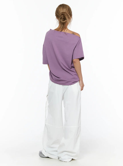 Star Studded Asymmetric Drawstring Tee CU524 Purple back shot on model showing clean plain back with asymmetric off-shoulder neckline and soft cotton fabric, paired with white wide-leg pants