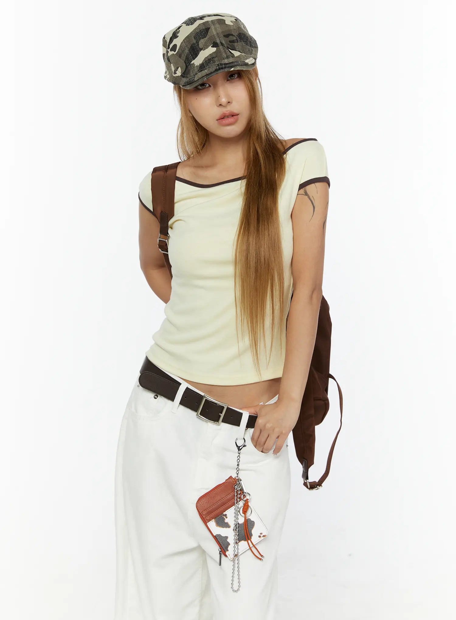 Staria vintage Cap IL503 camouflage full-body front shot on model styled with cream top, white trousers, brown belt and backpack