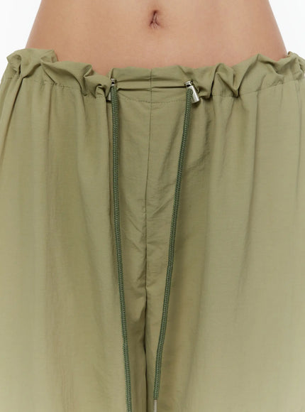String Pocket Wide Pants CU526 Dark green close-up detail of elastic drawstring waistband with silver cord-lock tips and ruched fabric on model