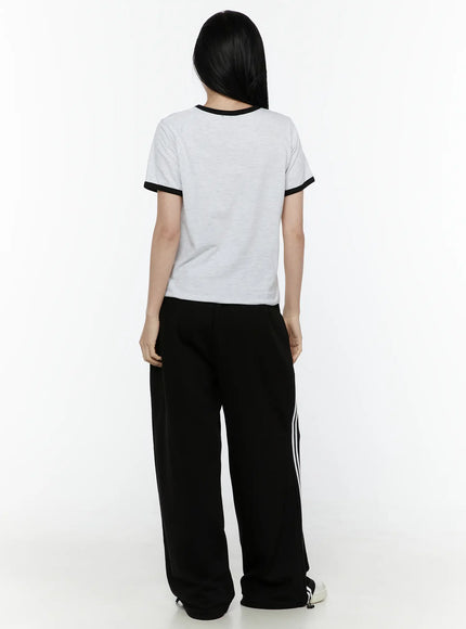 Stripe Detail Sweatpants IL506 Black back full-body model shot, styled with grey ringer tee, wide-leg track pants showing rear waistband and white side stripes