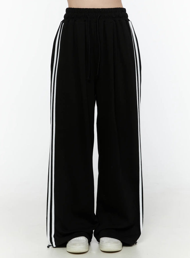 LEWKIN Stripe Detail Sweatpants IL506 Black front view on model, headless shot, wide-leg silhouette with white side stripes, elastic drawstring waist, S/M